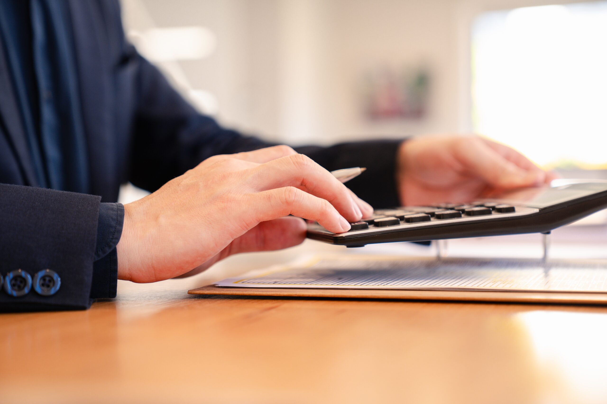 Businessman,Using,A,Calculator,While,Reviewing,Financial,Documents,,Symbolizing,Accounting,